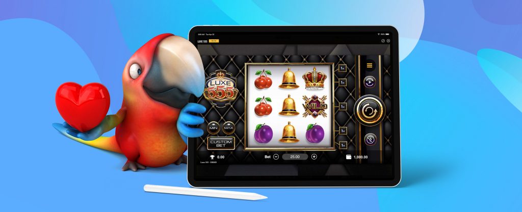 A colorful, 3D-animated toucan holding a red love heart with one hand, peeks around the screen of an iPad which is featuring a screenshot from the popular SlotsLV slot game, Luxe 555. Shown are three reels with various symbols against a luxurious black backdrop.