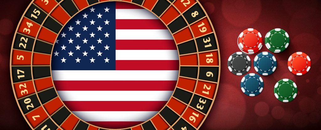 Casino roulette wheel with red and black numbers, the US flag in the center and casino chips on the side.